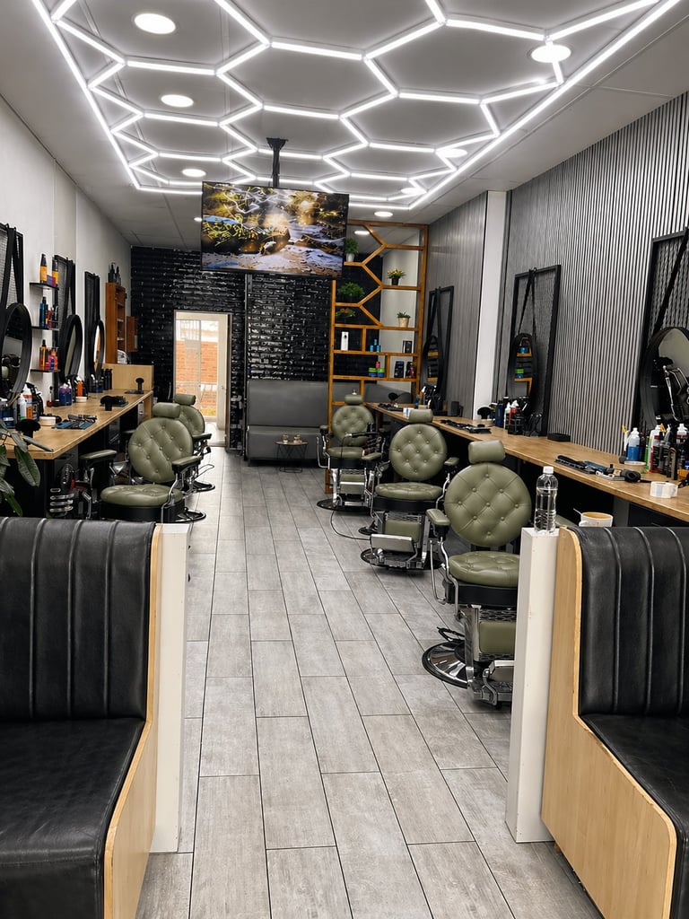 Modern barbershop interior with hexagonal neon ceiling lights, barber chairs with green upholstery, and black brick accent wall