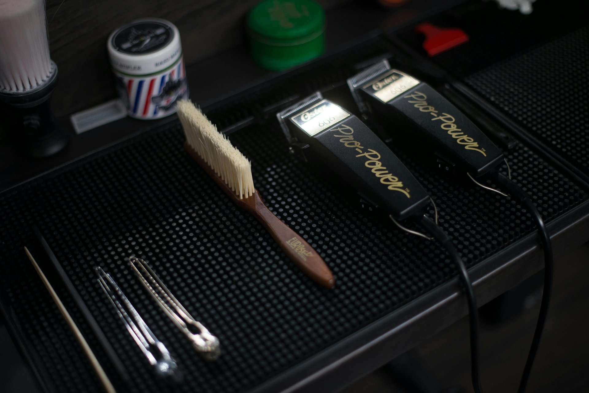 Makeup brushes and cosmetic products arranged on a black textured surface with containers in background